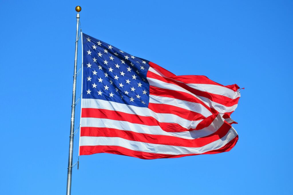 Majestic American flag waving against a bright blue sky, symbolizing freedom and patriotism.